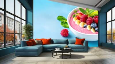 Colorful smoothie bowl with fresh fruits and mint leaves on a light blue background. Perfect for healthy eating and breakfast inspiration. Wall mural