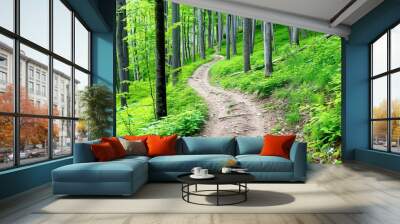 Narrow dirt path winding through lush, green forest with tall trees and vibrant foliage under natural daylight. Wall mural