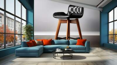 A modern bar stool with a black leather seat and wooden legs. Wall mural