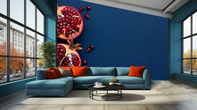  photo of cut in halves pomegranate fruit on a solid dark-blue background with copy space Wall mural