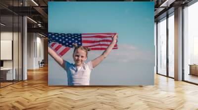 American flag. Little patriotic happy girl holding an american flag waving on nature outdoor blue sky background. USA celebrate 4th of July. Wall mural