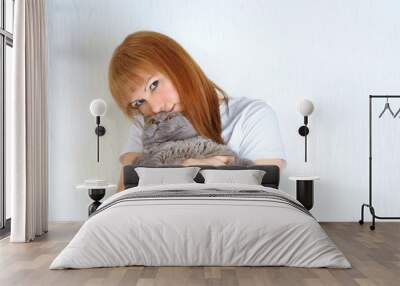 Attractive middle aged woman with cute british shorthair cat resting at home.A woman in the period of menopause. Blond / red hair mature senior female relaxing at home and embracing pet. Wall mural