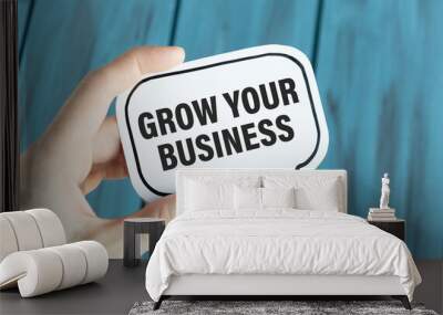 Closeup on businessman holding a card with text GROW YOUR BUSINESS, business concept image with soft focus background Wall mural