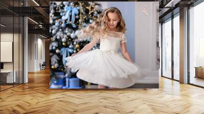 Merry Christmas celebration. Beautiful little girl in a amazing dress sitting near the Christmas tree. Christmas miracles. Happy New Year Wall mural