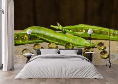 Green peas and omega-3 capsules on wooden background Wall mural