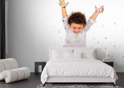 Happy funny curly hair child boy with confetti on white background. Little boy having fun celebrating birthday. Wall mural