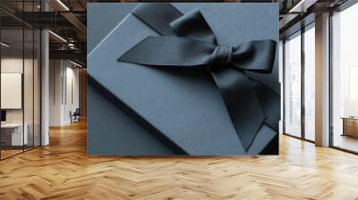 Black gift box on a dark contrasted background, decorated with a textured bow and feathers, creating a romantic atmosphere. Typically used for birthday, anniversary presents, gift cards, post cards. Wall mural