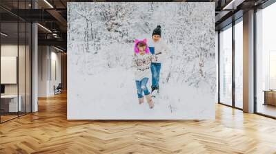 Children have fun playing in the snow. boy and girl running around in winter park. winter holidays Wall mural