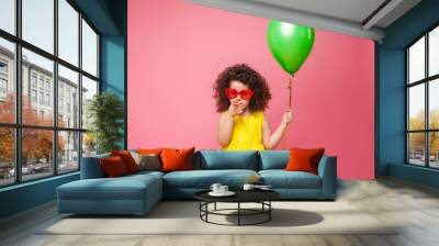 Happy birthday celebration with flying balloons of a charming cute little girl in a yellow dress isolated on a pink background. Wall mural