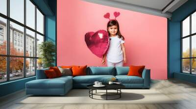 valentine's day, Little girl in holding a big balloon in the shape of a heart on a pink background. Wall mural