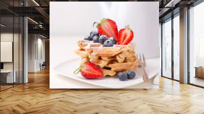 Stack of delicious . waffles with blueberries and sliced strawberries .close-up on white table with white.teapot .from the back Wall mural