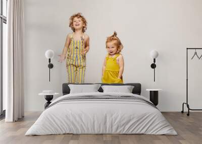 Two cute stylish children, boy and girl in fashionable summer clothes posing on a beige background. Isolated in full length with copy space Wall mural