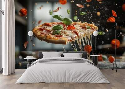 A delicious slice of pizza with melted cheese, pepperoni, and fresh basil appears to float, surrounded by flying ingredients and a blurred kitchen background Wall mural