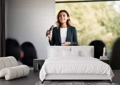 A confident female executive masterfully delivers a business presentation in a boardroom, engaging her audience during an informative workshop Wall mural