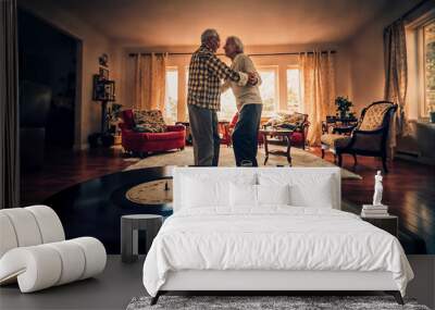 An affectionate senior couple dances at home to music from a vintage record player. Wall mural