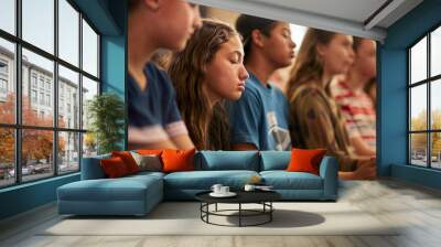 Candid shot of teenagers in a prayer group, displaying solemn expressions that capture a moment of deep spirituality and reflection.

 Wall mural