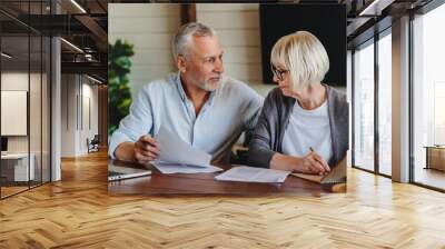 Aged couple signing and filling documents at home Wall mural