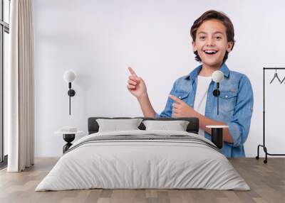 Amazed young male kid pointing at copy space isolated over white background Wall mural