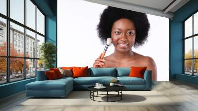 Attractive african young girl using make-up brush in bath towel isolated in white background Wall mural