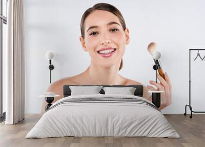 Beauty portrait of young smiling woman holding make up brush isolated over white background Wall mural