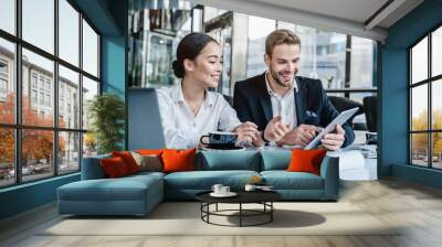 Business man sharing his ideas with tablet to asian female colleague Wall mural