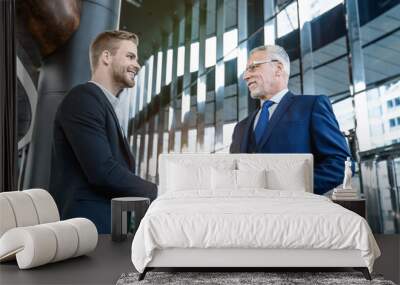 Business people meeting in a modern cafe with a handshake. Handshaking between male business partners after making a successful completed deal indoors. Wall mural