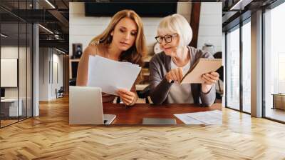 Caucasian woman explaining some documentation or bill papers to parent at home Wall mural