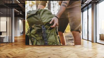 Close up of male hiker holding his camping backpack. Traveler opening backpack while traveling in beautiful wood Wall mural