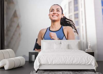 Close up photo of running beautiful young woman jogger smiling while jogging in urban area Wall mural