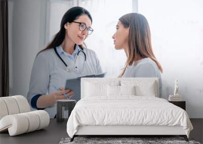 Doctor talking to female patient in working cabinet at hospital Wall mural