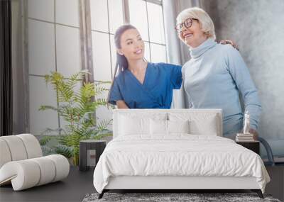 Female asian nurse helping senior woman to walk with walker at home Wall mural