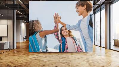 Happy children giving high five each other standing near school outdoors Wall mural