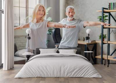 Mature couple practicing yoga and performing warrior yoga pose together Wall mural