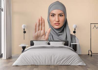 Nice-looking young serious islamic arabian middle eastern muslim woman in grey hijab showing stop warning sign isolated over beige background. Forbidden, prohibited concept, saying no Wall mural