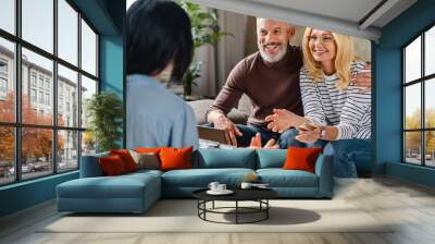 personal financial adviser explaining terms of contract to happy middle aged couple on tablet Wall mural