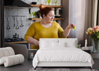 Plus size , fat caucasian woman learning to make salad and healthy food from social media adding vegetables to salad bowl ,Social distancing, stay at home concept Wall mural