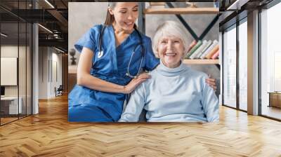 Portrait of happy elderly woman with female caretaker indoors Wall mural