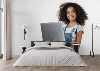 Portrait of little girl holding laptop computer while standing and looking at camera isolated over white background Wall mural