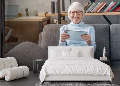 Portrait of smiling mature woman using digital tablet on sofa at home Wall mural