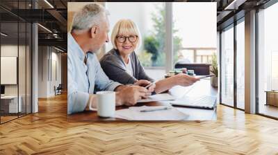 Senior couple doing home finances using laptop indoors Wall mural