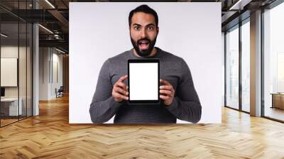 Shocked young handsome Middle Eastern man with blank tablet in casual attire isolated over white background Wall mural