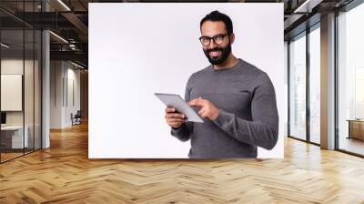 Side view photo of young handsome arab man using tablet in casual outfit isolated over white background Wall mural