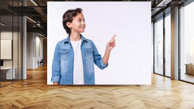 Side view portrait of young 10s boy in casual outfit pointing at copy space isolated over white background Wall mural