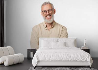 Smart caucasian mature middle-aged freelancer man in beige shirt wearing glasses looking at camera with arms crossed isolated in white background Wall mural