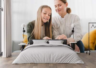 Smiling happy caucasian family of mother and daughter saving money, putting coins into bank, planning future, paying bills loan together. Nest egg concept. Wall mural