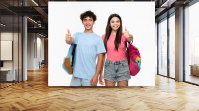 Smiling high school pupils students teenagers classmates boy girl friends in casual clothes with bags showing thumb up sign gesture isolated on white background. Education back to school concept Wall mural