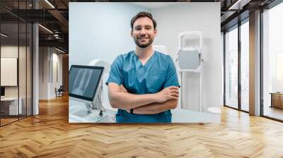 Smiling young doctor medical worker specialist radiologist standing in his cabinet office in modern clinic crossed folded arms looking at camera. Fluorography roentgenography x-ray concept Wall mural