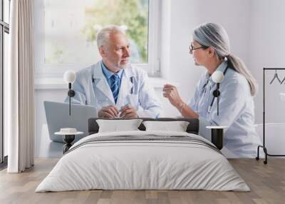 Two senior doctors discussing test results on desktop in hospital Wall mural