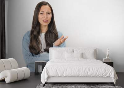 Young asian woman unhappy for not understand something over white isolated background Wall mural