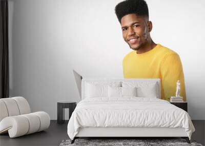 Young cheerful african man using laptop computer standing isolated over white background Wall mural